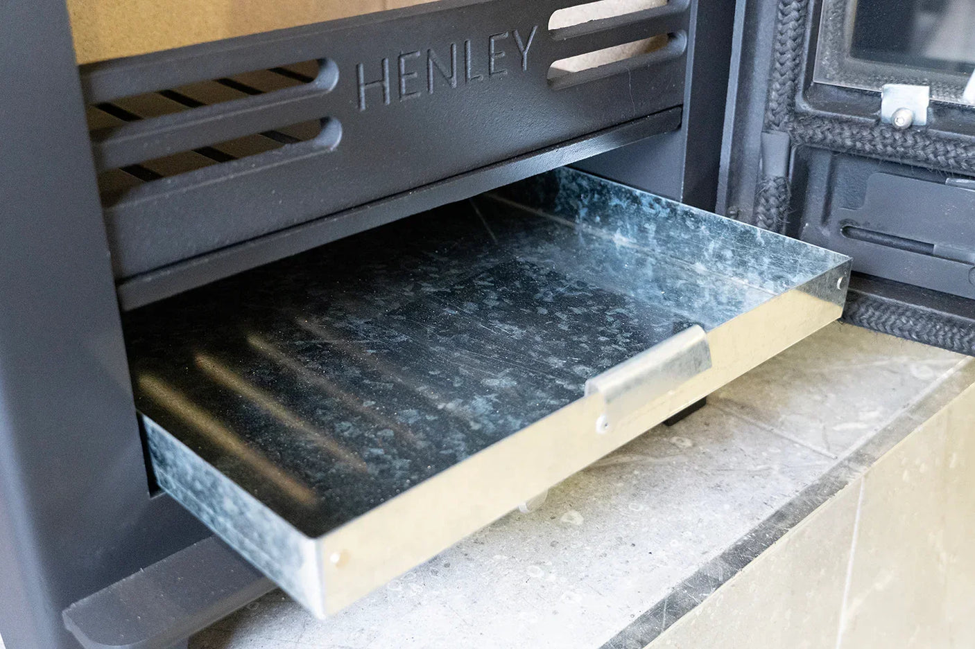 Metal ash tray pulled out from stove compartment with front handle visible