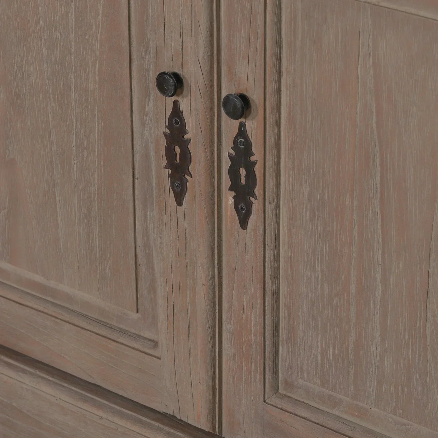 Close up of wooden cabinet doors with black metal handles and vintage keyhole plates