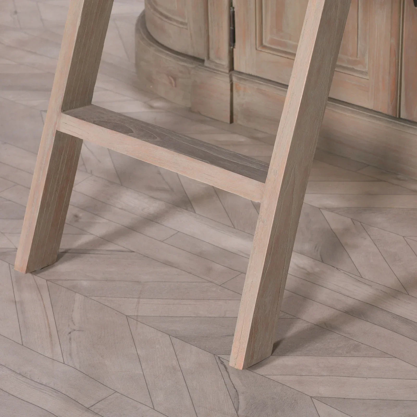 Close-up of wooden furniture leg on chevron parquet flooring