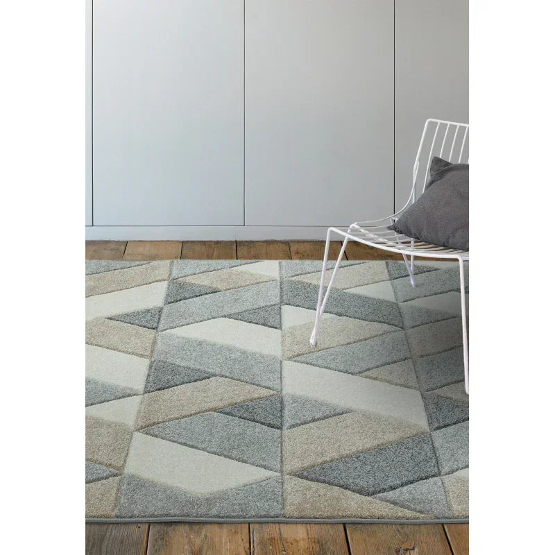 Geometric pattern area rug in grey tones on wooden floor with white metal chair