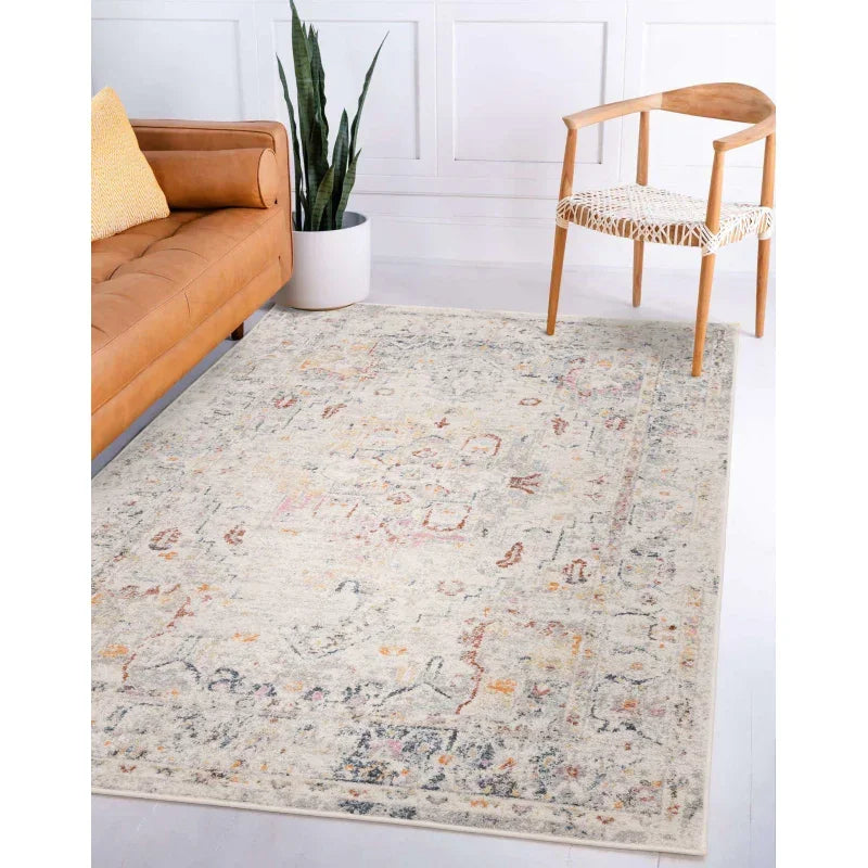 Neutral patterned area rug in living room with tan sofa and wooden accent chair