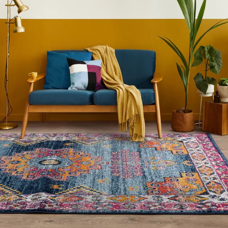 Blue patterned area rug in living room with wooden sofa and colorful cushions