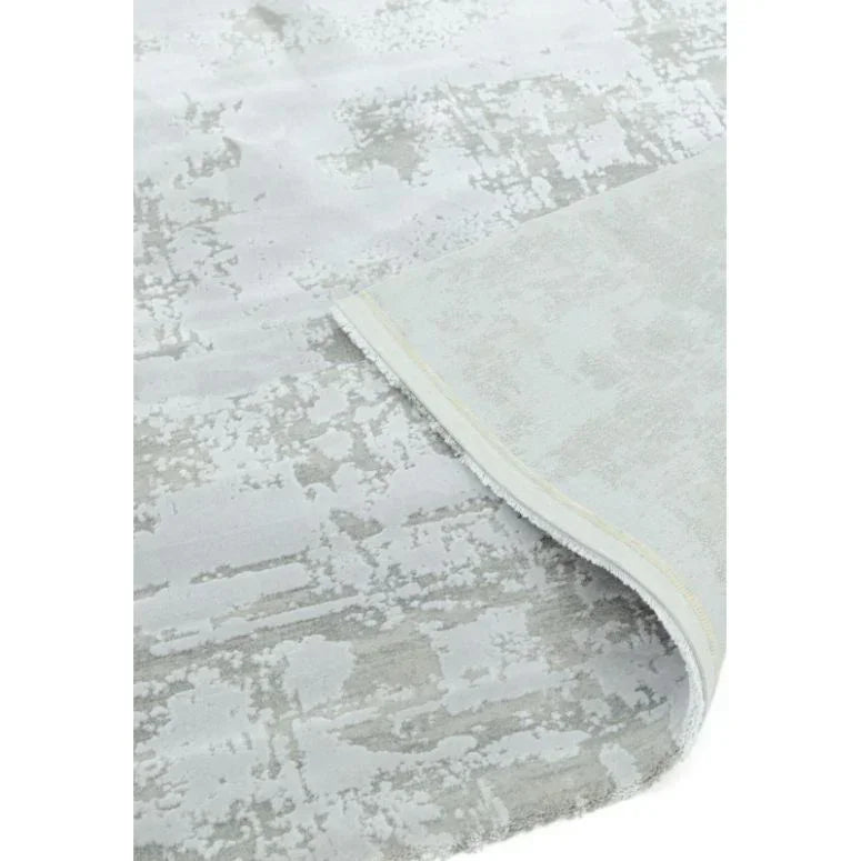 Modern grey area rug with abstract pattern and corner lifted to show texture detail