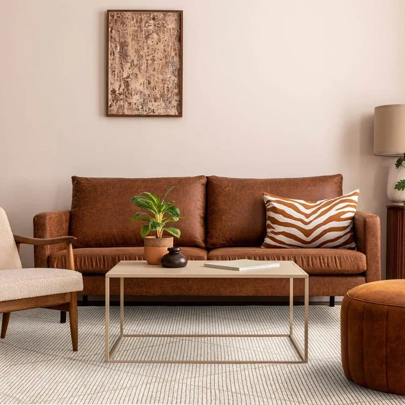 Brown leather sofa with patterned cushion, coffee table, and indoor plant in modern living room