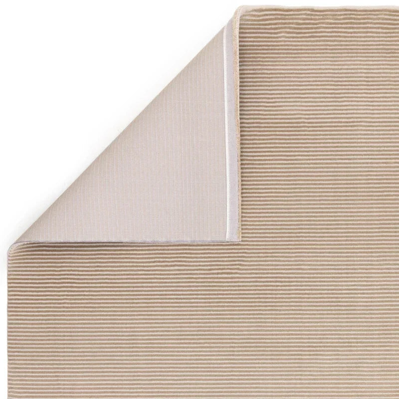 Beige striped area rug with corner folded to show backing detail