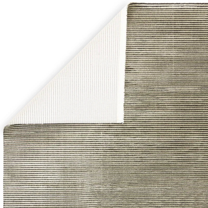 Beige striped area rug with corner lifted to show textured backing
