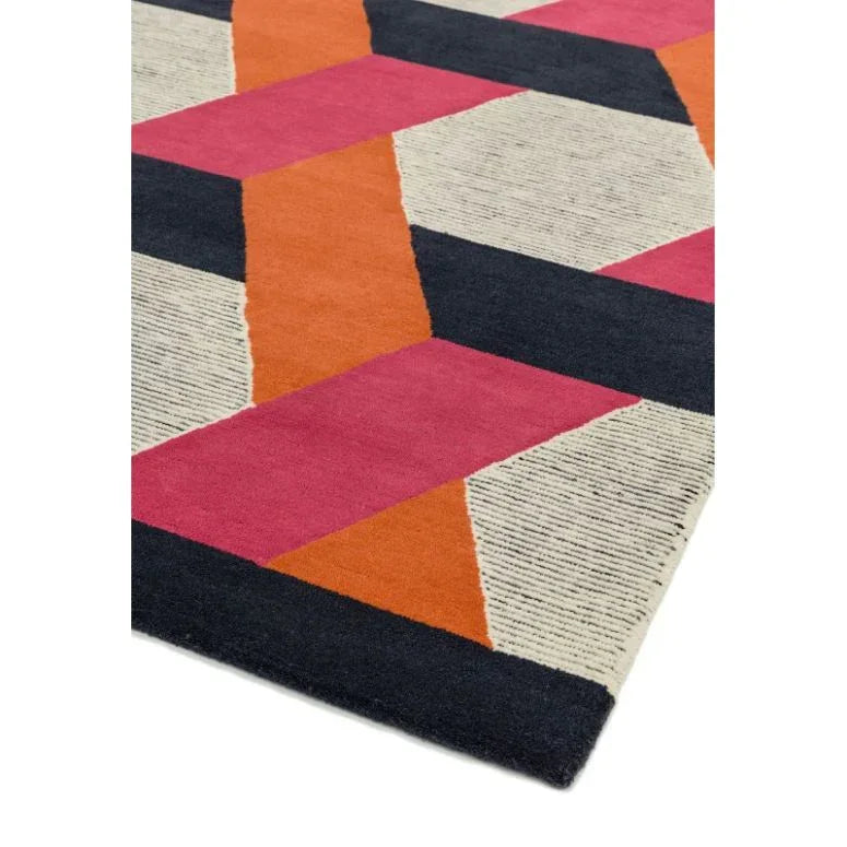 Geometric area rug with pink, orange, black, and cream blocks on a flat surface