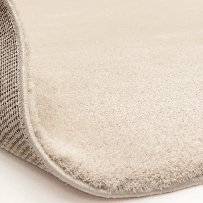 Closeup of cream area rug with textured pile and checked backing