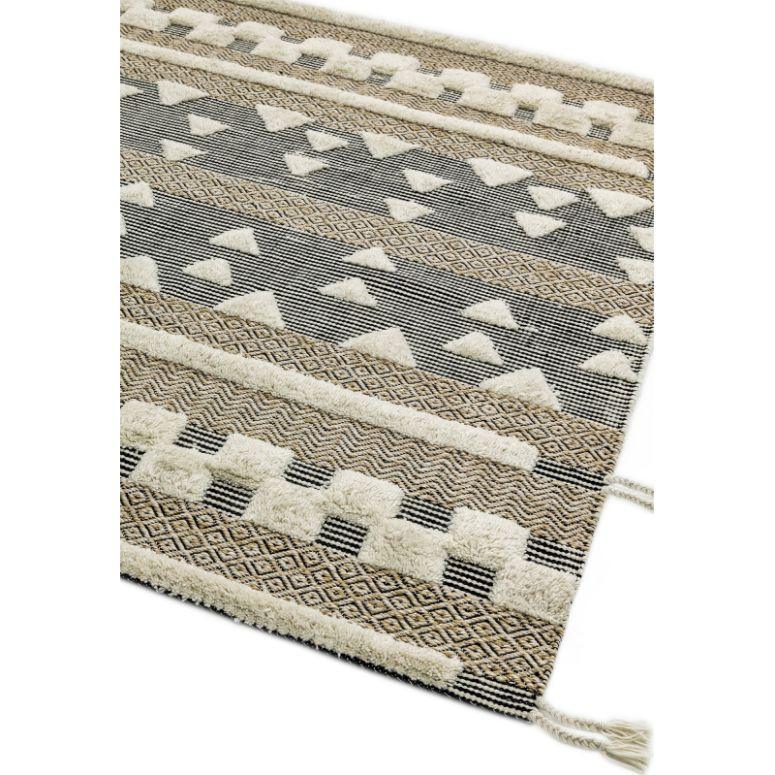Geometric patterned area rug in beige, cream, and grey with textured design and fringed edge