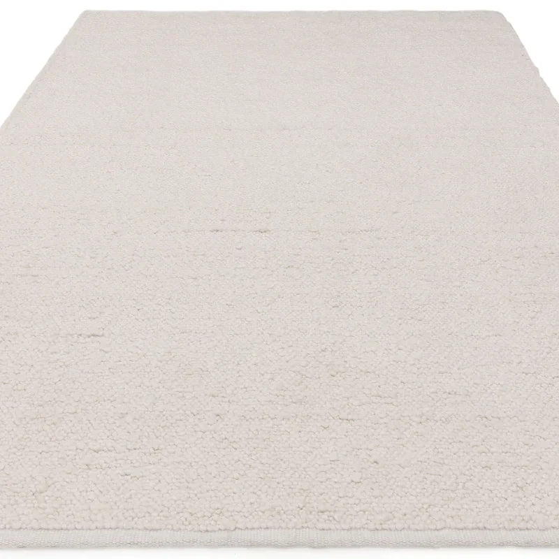 Cream wool floor rug with textured loop pile design, shown from a low angle