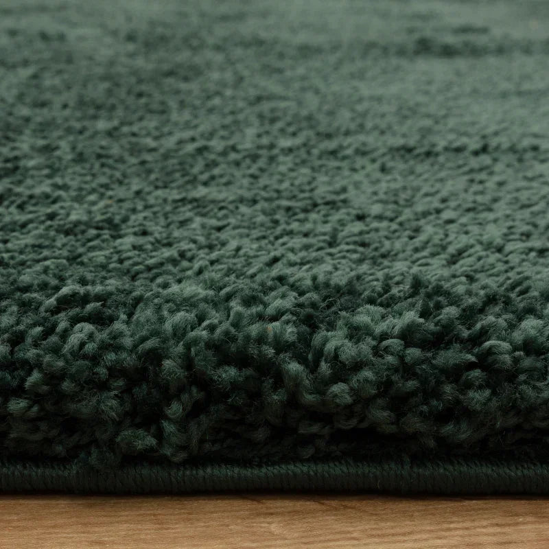 Deep green shaggy rug closeup showing thick pile texture and soft fibres on wooden floor