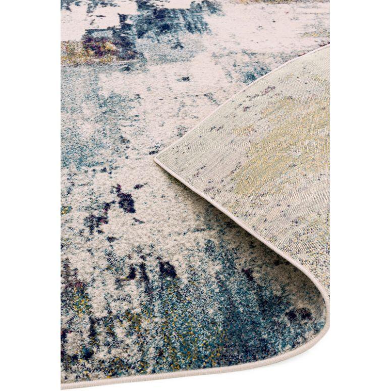 Abstract area rug with blue and cream pattern, close corner flipped to show backing