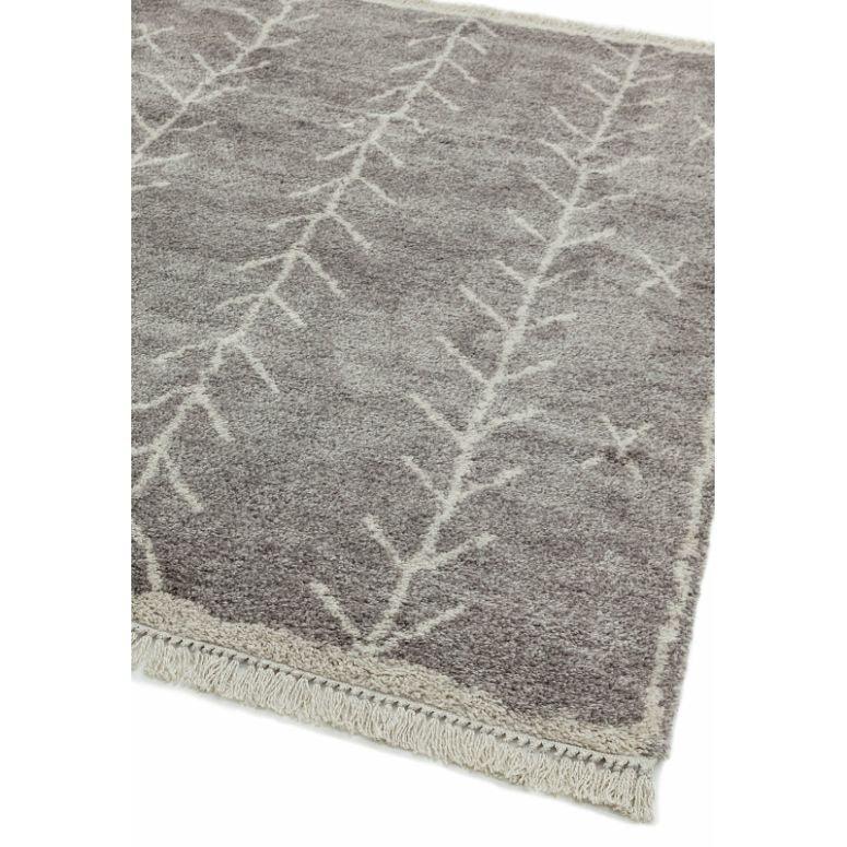 Grey area rug with subtle white geometric branches and fringe edge detail