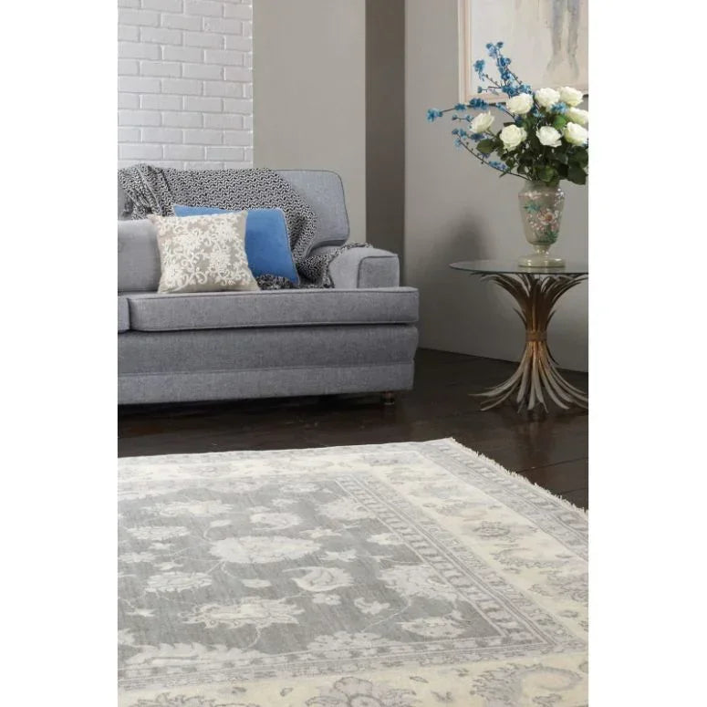 Grey and cream patterned rug on dark wood floor beside grey sofa with accent cushions