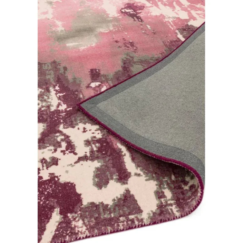 Abstract pink and cream area rug with corner folded to show backing