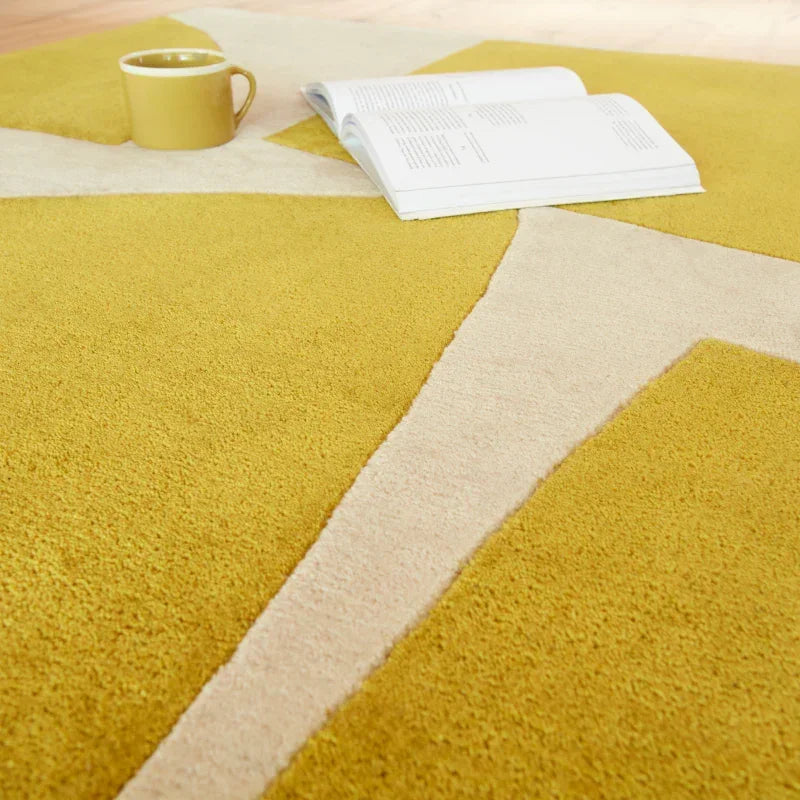 Yellow geometric area rug with open book and mug placed on top