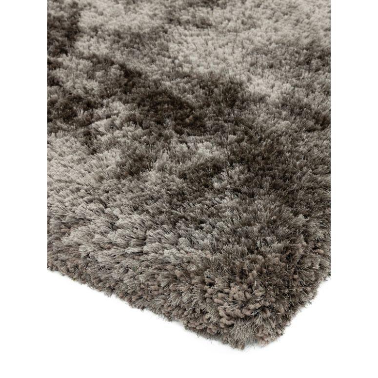 Corner of a plush shaggy rug in grey tones with thick pile texture