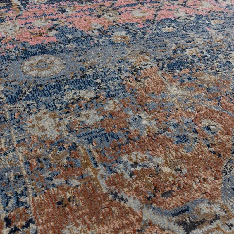 Close view of patterned area rug with blue, rust, and beige distressed design