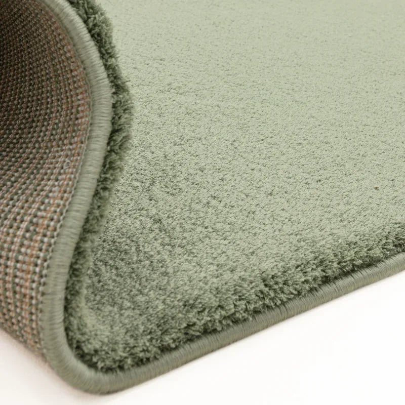 Close up of sage green rug with soft pile and stitched edge detail