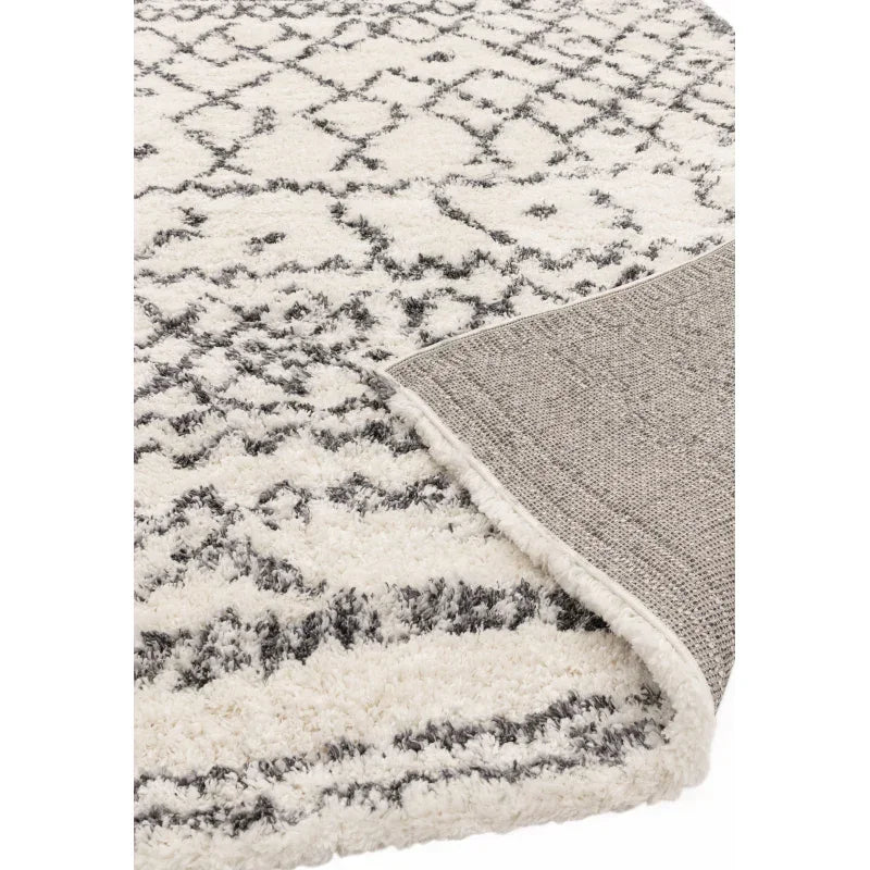 White and grey shaggy rug with geometric pattern and corner folded to show backing