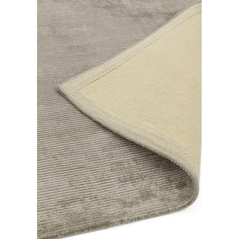 Closeup grey ribbed rug with corner flipped to show beige underside and texture detail