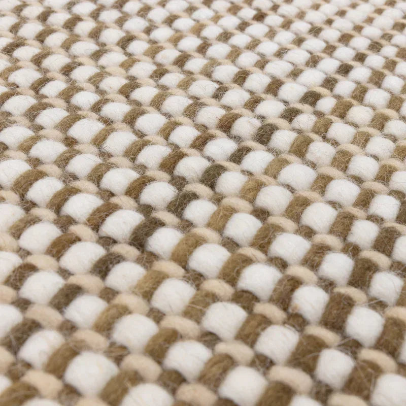 Closeup of woven wool rug in beige and cream, showing thick textured weave detail