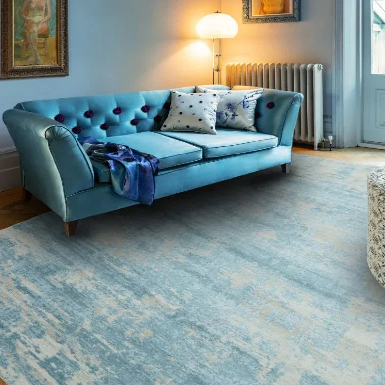 Blue velvet sofa with scatter cushions in modern living room on light blue patterned rug