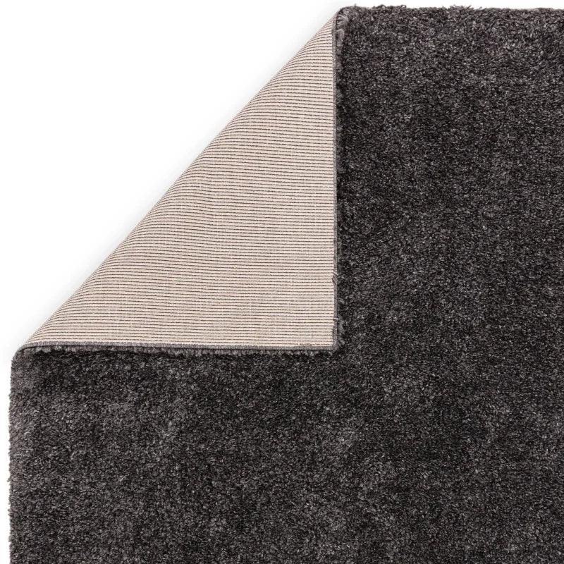 Dark grey shaggy rug with exposed corner showing textured backing