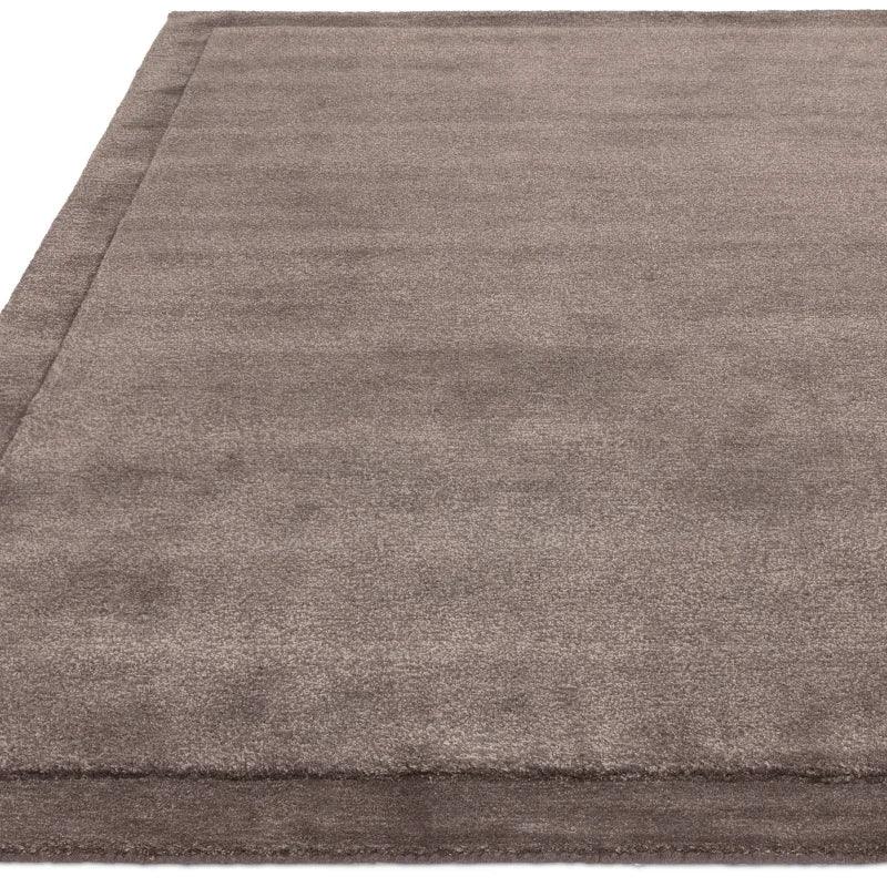 Taupe area rug with soft texture and subtle border detail, shown from corner angle