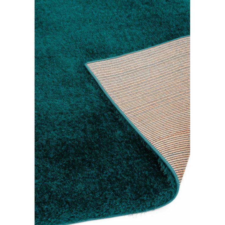 Teal shaggy rug with corner flipped to show striped non-slip backing