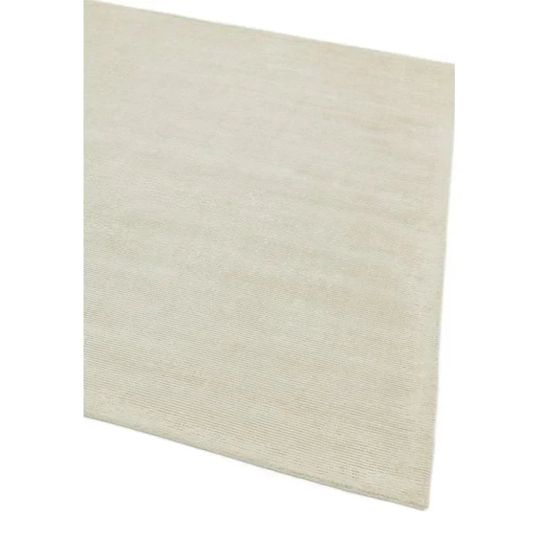Beige area rug with subtle texture, close-up of corner and low profile design