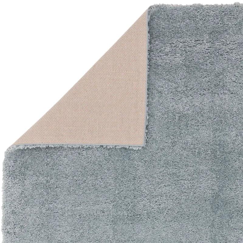 Grey shaggy rug with corner turned to show textured non-slip backing