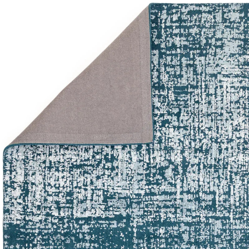 Blue and grey abstract pattern rug with corner turned to show backing