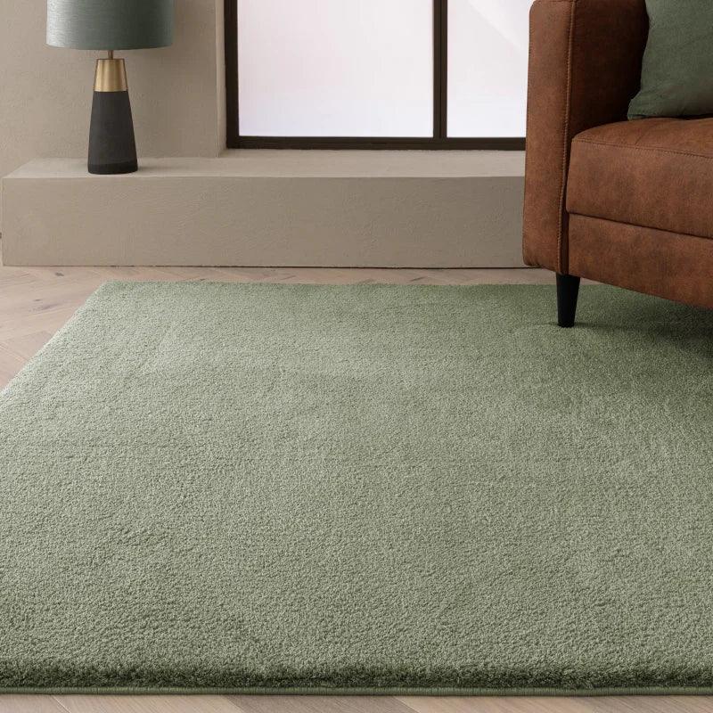 Sage green area rug in modern living room with brown sofa and contemporary lamp