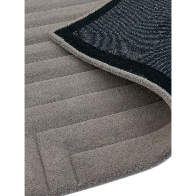 Grey area rug with textured geometric pattern and visible underside corner