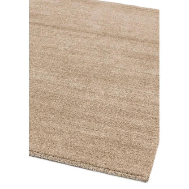 Beige area rug with subtle texture and finished edges viewed from an angle