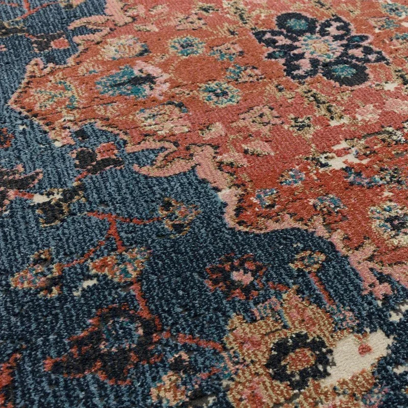 Close-up of patterned area rug with blue and rust floral design and textured surface