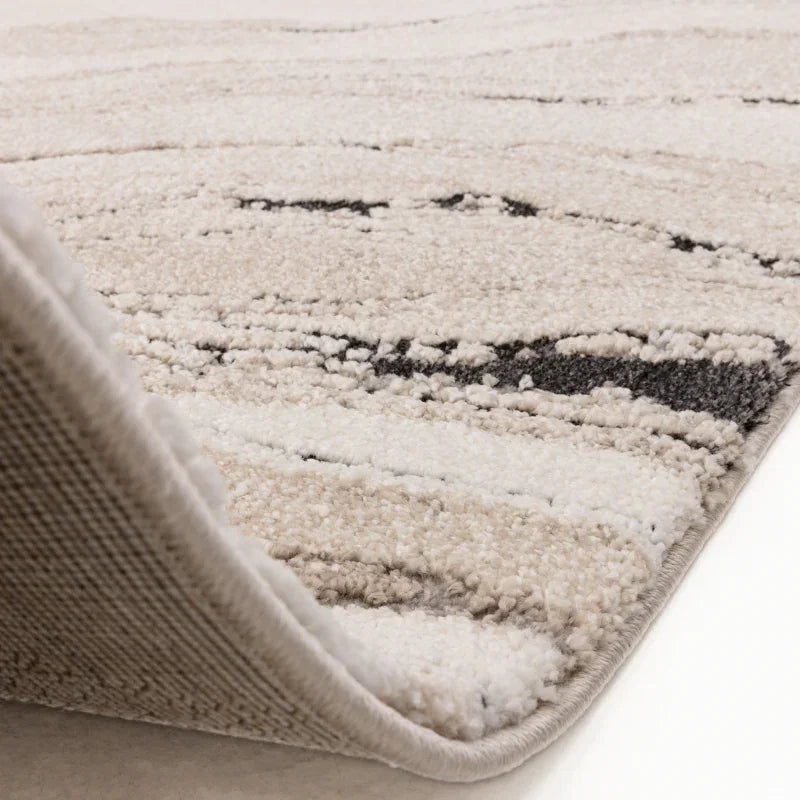 Beige and cream area rug with textured pile, close-up corner folded to show thickness