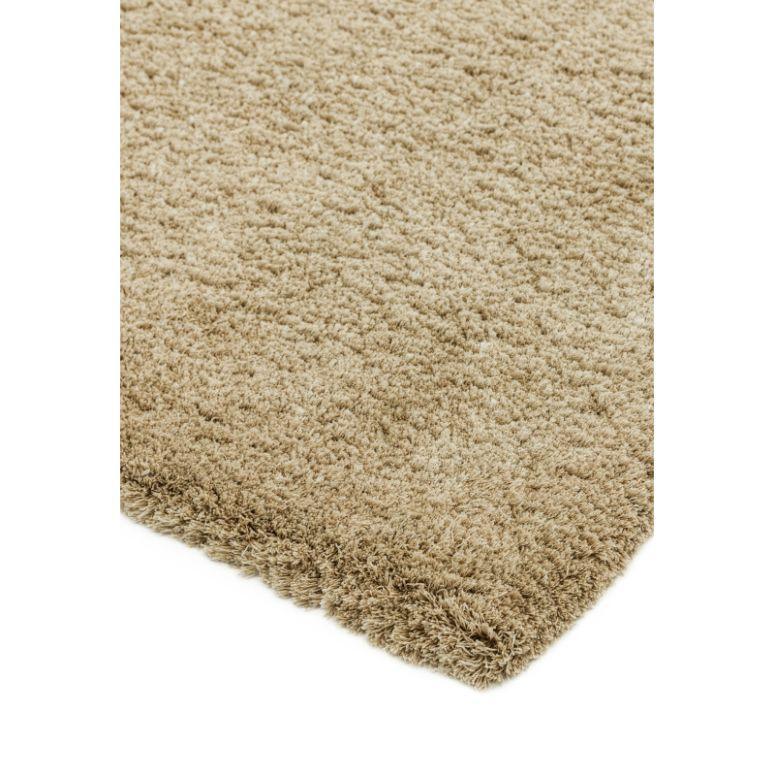 Beige shaggy rug corner with thick soft pile, close-up of texture and edge