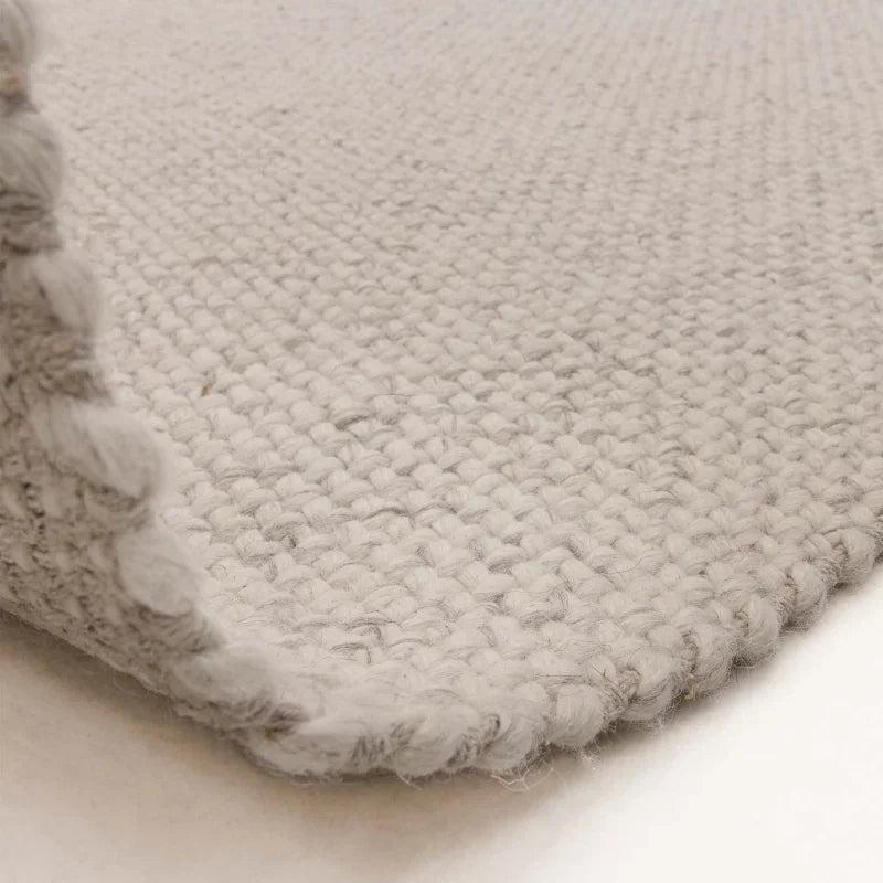 Close up of light grey woven wool rug corner and textured surface