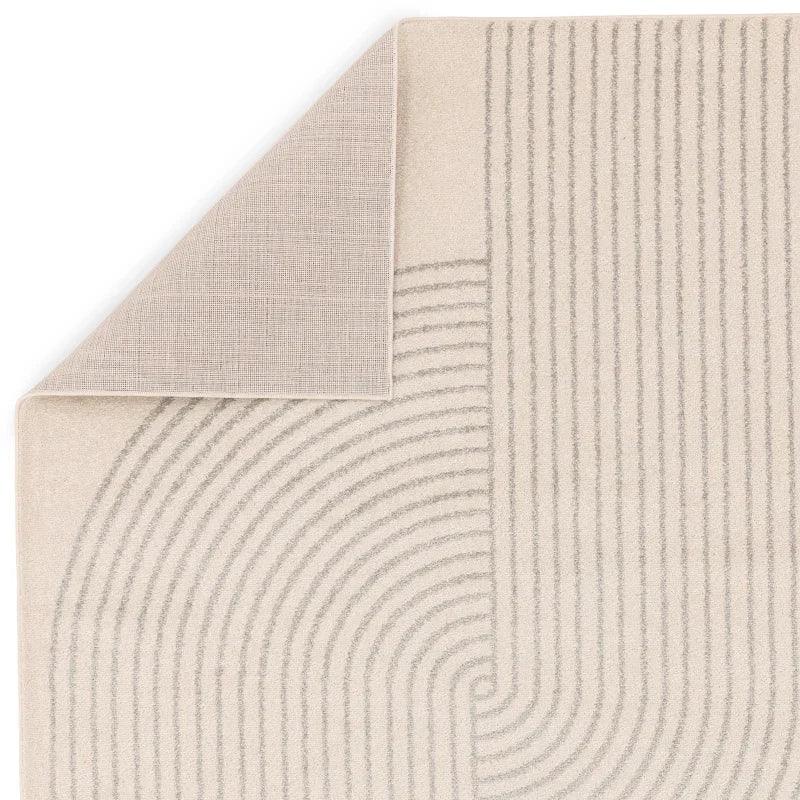 Beige modern rug with geometric line pattern and folded corner showing textured backing