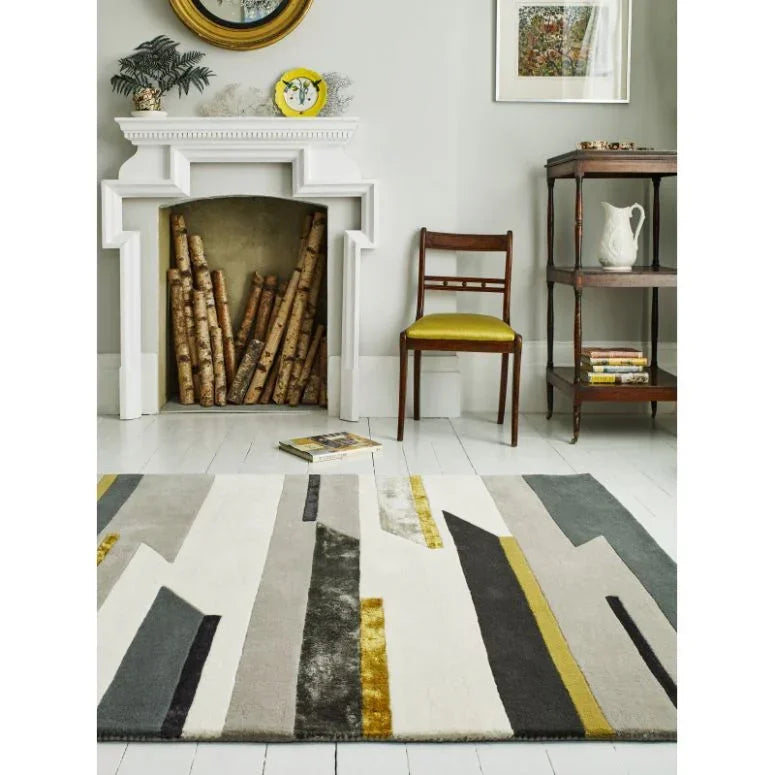 Modern geometric rug with yellow, grey, and cream shapes on white wood flooring in living room