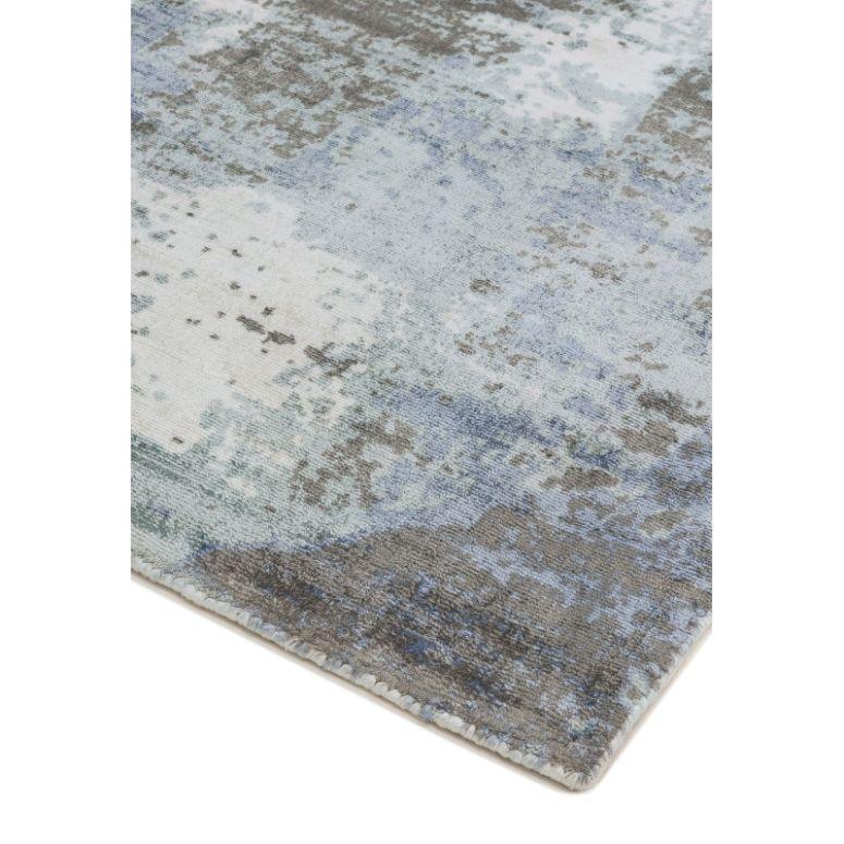 Corner of abstract area rug with blue, grey, and cream pattern on soft woven fabric