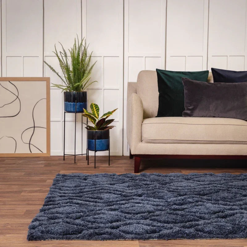 Navy blue shaggy rug in modern living room with beige sofa, velvet cushions, and indoor plants