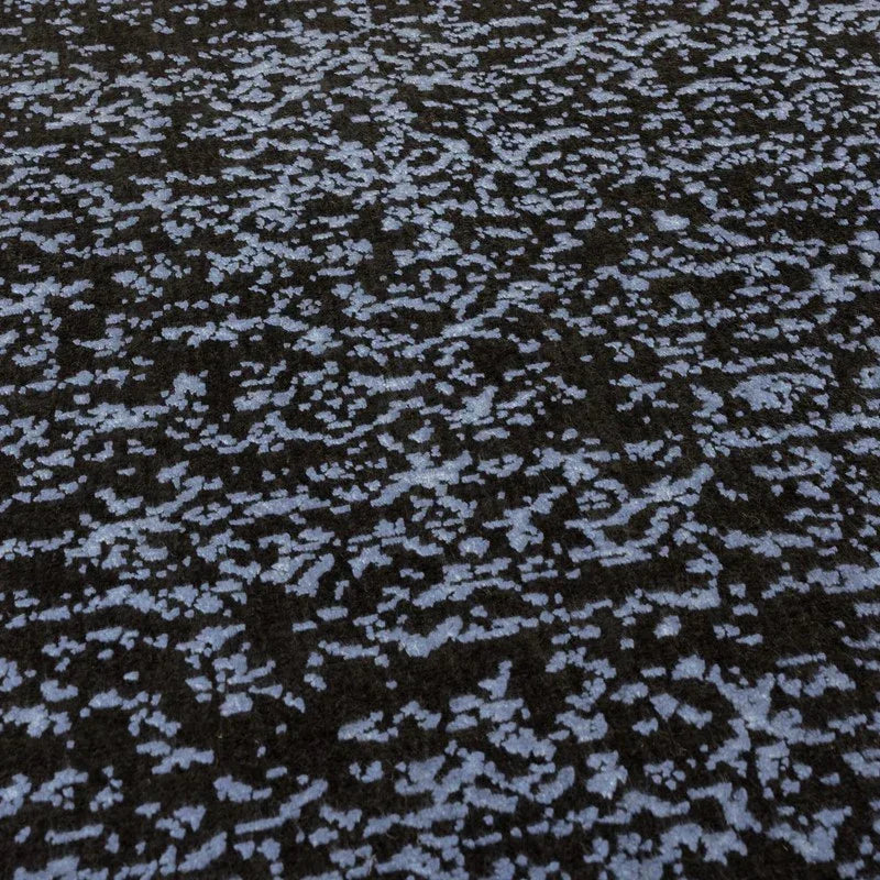 Textured area rug with blue and black abstract pattern, close-up of surface