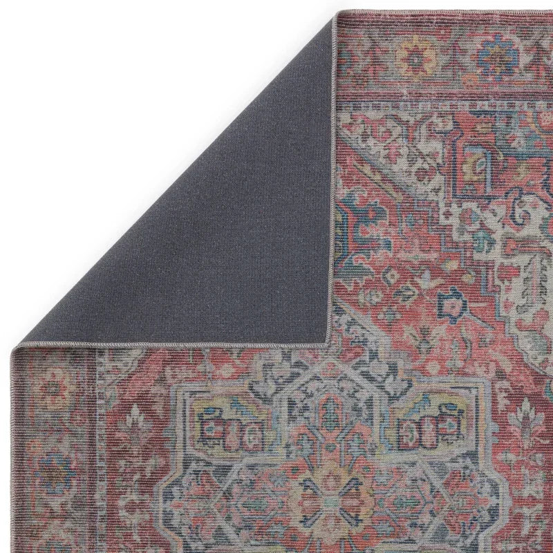 Vintage style area rug with red and blue patterns and folded corner showing backing