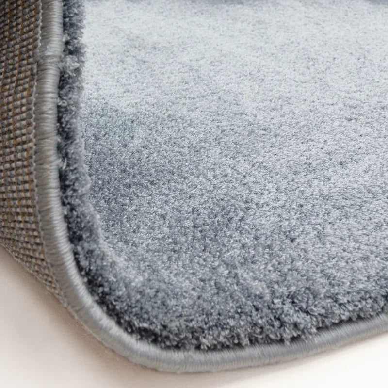 Close-up of light grey carpet with soft pile and stitched edge