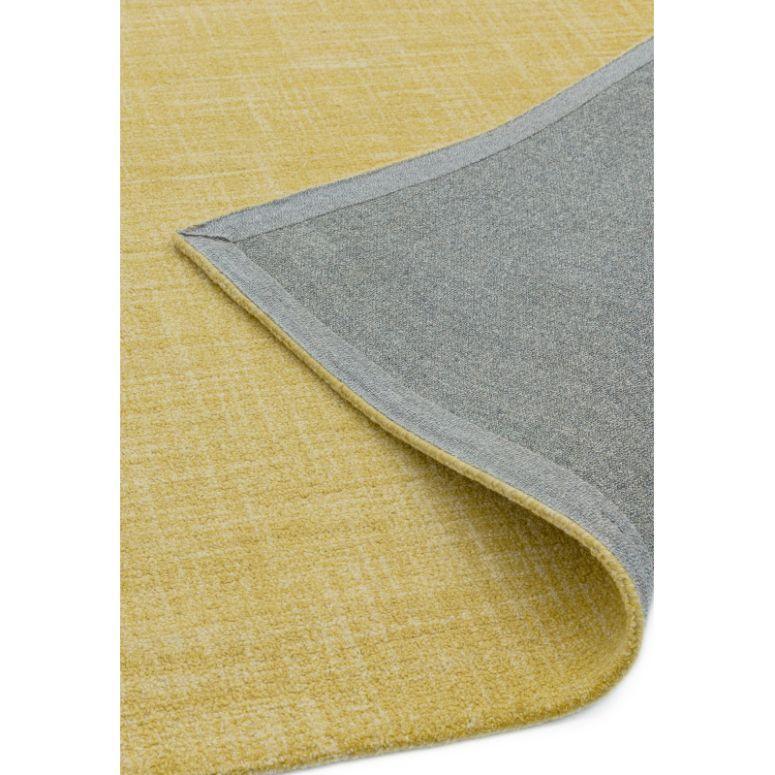 Yellow area rug with visible corner showing grey underside and stitched edge