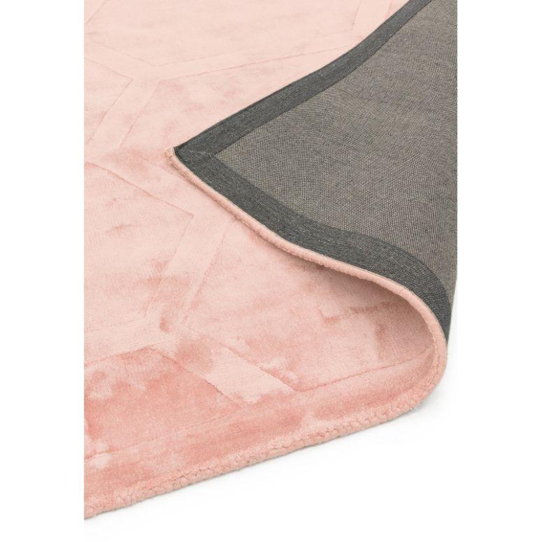 Blush pink area rug with geometric pattern, close-up showing corner and backing