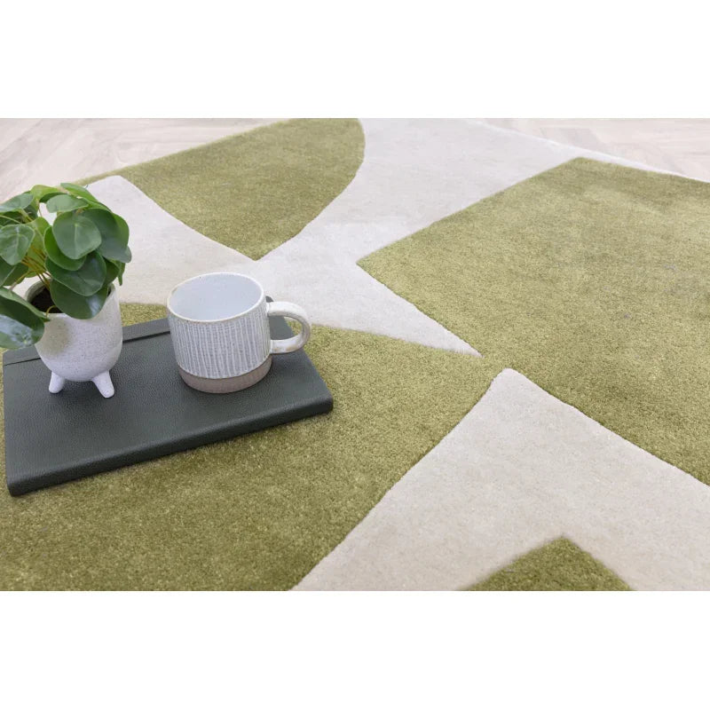Green and cream patterned area rug with tray, mug, and small plant on top
